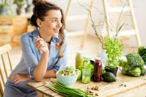 Woman with salad and surrounded by vibrant whole foods has the motivation to eat healthy